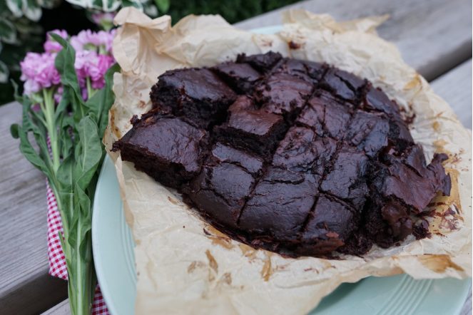 Beetroot brownies cut into squares on baking paper, with pink flowers