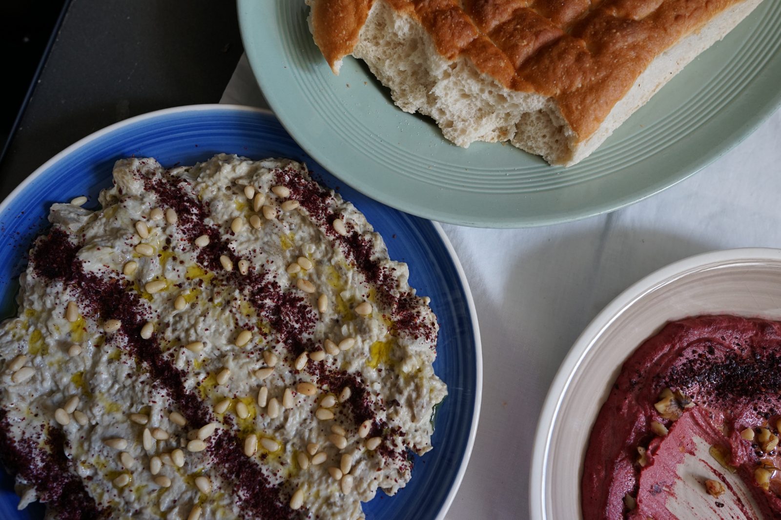 Baba ganoush with pine nuts and sumac, beetroot and walnut dip, and a torn loaf of bread